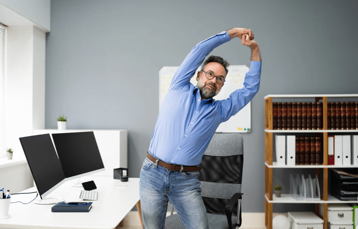 A person stretching at their work from home setup desk